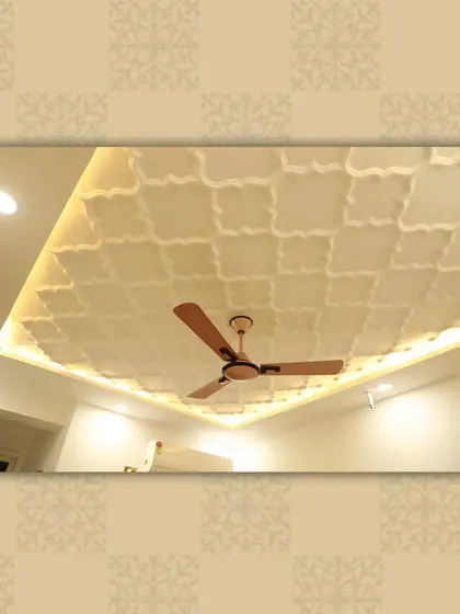 An elegant ceiling featuring a repeating geometric pattern, with cove lighting around the perimeter to highlight the intricate design.