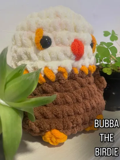 Here is another version of Bubba the Birdie, designed to look like a majestic eagle. The combination of white, brown, and orange yarn brings this powerful bird to life in a cute, cuddly form.