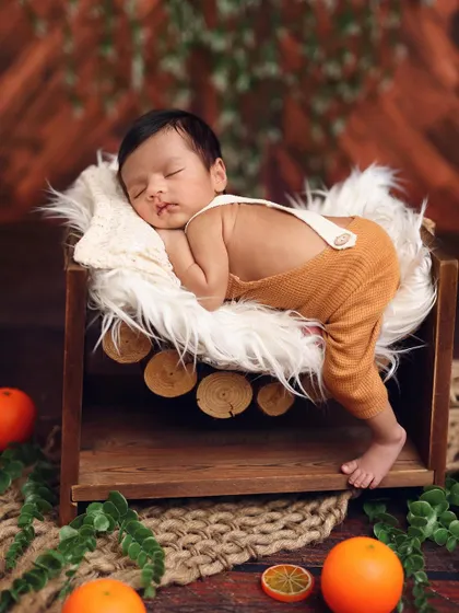 Another angle of the rustic log bed setup, showcasing the baby's peaceful pose and the warm, earthy tones of the props.