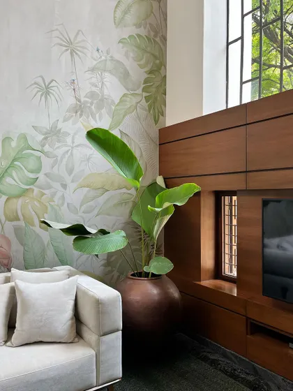 A close-up of the living room, showing the hand-painted mural next to the custom wooden media unit. A large indoor plant further enhances the connection to nature.