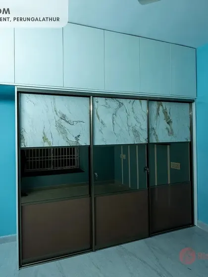 Master bedroom at our Perungalathur site, featuring a three-door sliding wardrobe with a combination of mirrored, marble-finish, and bronze panels for a sophisticated look.