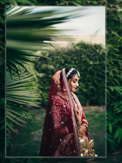 An artistic shot of the bride framed by palm leaves. This composition adds depth and a touch of nature to the classic bridal portrait.
