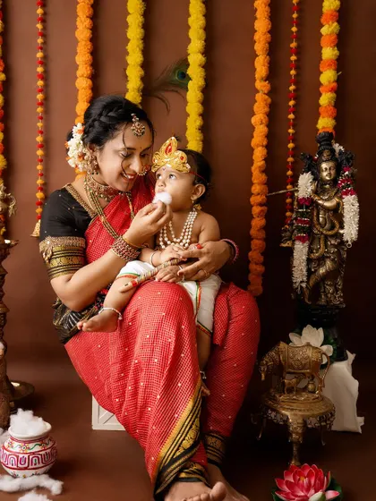 A sweet moment as a mother feeds her little Krishna a piece of cotton "butter".