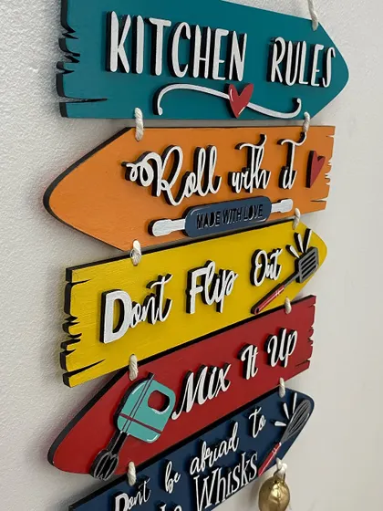 Another angle of the kitchen wall decor, highlighting the bright colors and the rustic bells that add a charming touch.