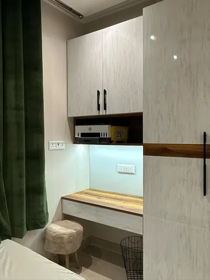 This guest room features a built-in study unit with overhead storage, seamlessly integrated with the wardrobe. The dark green velvet curtain adds a touch of drama and luxury.