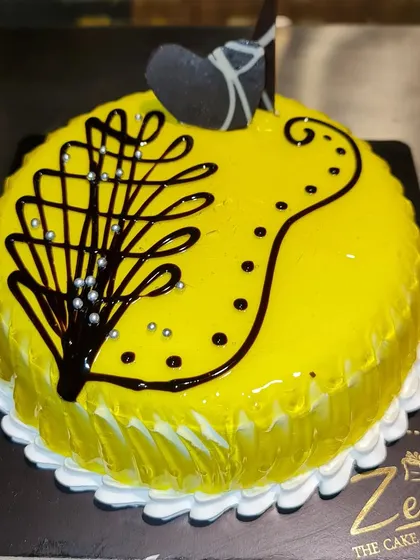 A fresh and fruity pineapple cake with a new, modern design. The bright yellow glaze is decorated with an artistic chocolate swirl.
