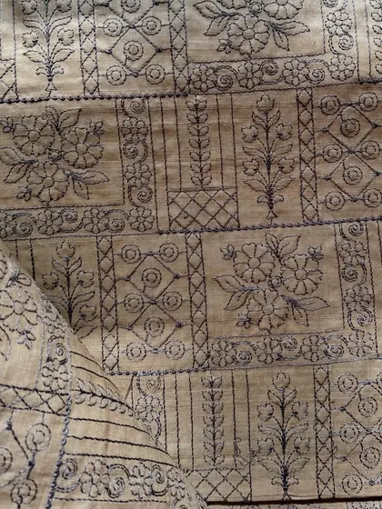 A close-up of the detailed embroidery on our natural Tussar silk. This fabric is a testament to traditional craftsmanship, perfect for creating heirloom pieces.