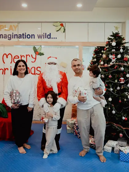 A family dressed in matching pajamas for our cozy Christmas party poses with Santa.