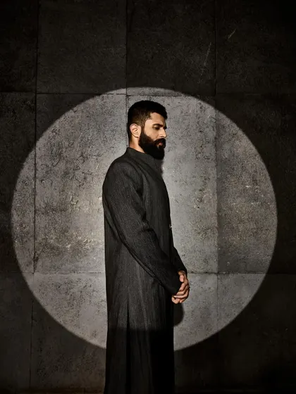 A contemplative pose. The dark, minimalist design allows the focus to be entirely on the silhouette and the wearer.