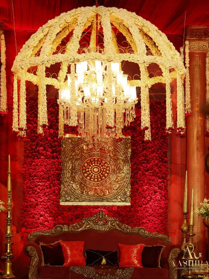 A close-up of the stage, where a wall of red roses and a traditional medallion were framed by a magnificent chandelier dressed in fragrant white tuberoses.