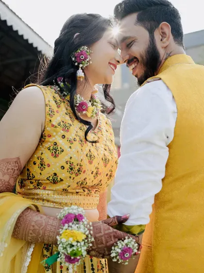 An intimate close-up of the couple, their faces close together, smiling. The bride's floral jewelry and the warm sunlight create a beautiful, romantic glow.
