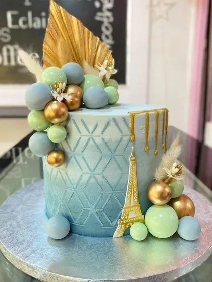 A final look at the modern Paris-themed cake, emphasizing the balance of the soft blue and green spheres against the metallic gold accents.