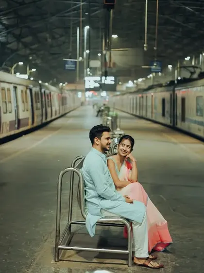 A wide-angle view of the couple at the train station, capturing the unique atmosphere and the motion of the trains.