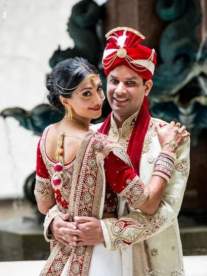 This couple showcases a beautiful blend of red and white. The bride's lehenga has a white base with heavy red and gold embroidery, while the groom's white sherwani is accented with a red stole and turban.