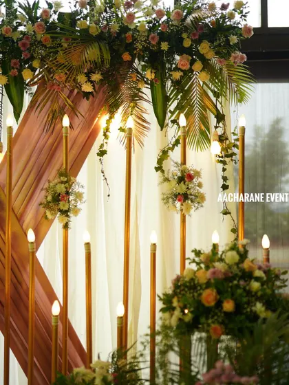Another detail shot of the modern stage decor, highlighting the combination of fresh flowers, greenery, and vertical light stands. These elements work together to create a warm and inviting atmosphere.