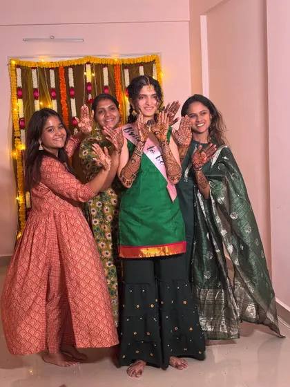 A happy group photo of the bride-to-be and her friends and family, all showing off their beautiful mehendi.