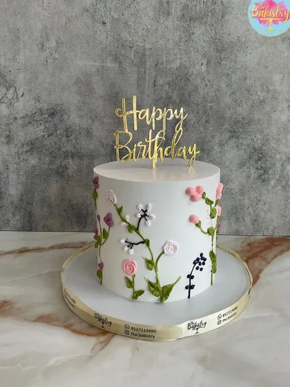 A simple and elegant white cake with delicate, hand-piped wildflowers climbing up the side.