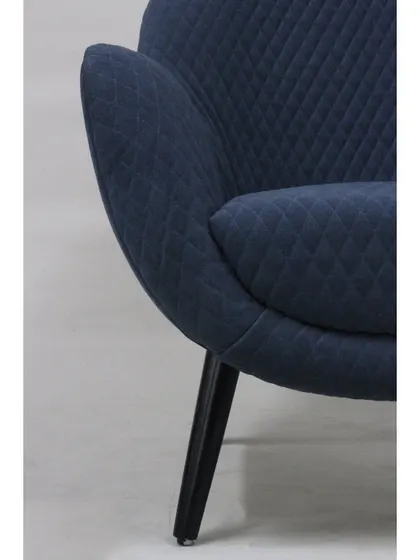 A detail of the quilted fabric and the chair's tapered leg, showing the subtle design elements that make it special.