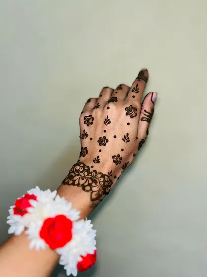 A single hand showing a minimal Eid design. The delicate floral wristband and scattered motifs are very elegant.