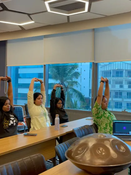 A group of employees stretching by the window in their office. Taking a moment to move the body and look away from the screen can significantly improve energy levels and productivity.