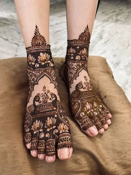 This foot mehndi is filled with beautiful peacocks and lotus flowers, designed to complement the bride's full-arm henna. The detail work is consistent across both hands and feet.