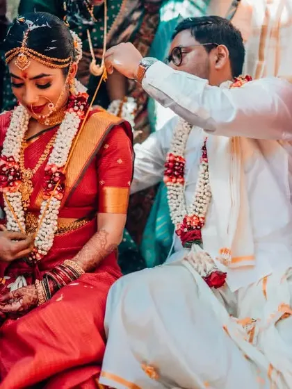 The pivotal moment of the groom tying the 'thali' or mangalsutra around the bride's neck in a South Indian ceremony.