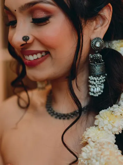 A close-up on this bride-to-be's happy smile during her Mehendi. The look is natural and fresh, with a focus on her radiant skin, a pretty nose pin, and statement jhumkas.