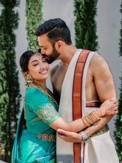 A sweet moment between the couple, framed by modern architecture. The groom's forehead kiss and the bride's happy smile make for a perfect portrait.