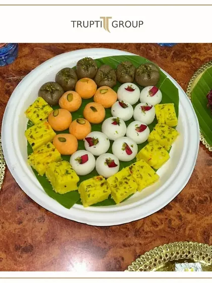 A colorful platter of assorted Indian mithai, including pedas and ladoos, beautifully arranged on a banana leaf.