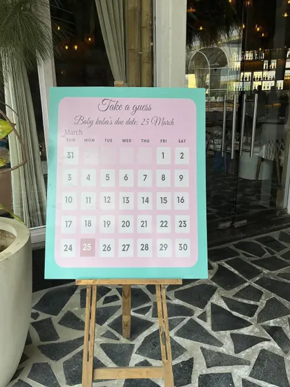 A close-up of the "Take a guess" due date calendar, a fun and interactive element for baby shower guests.