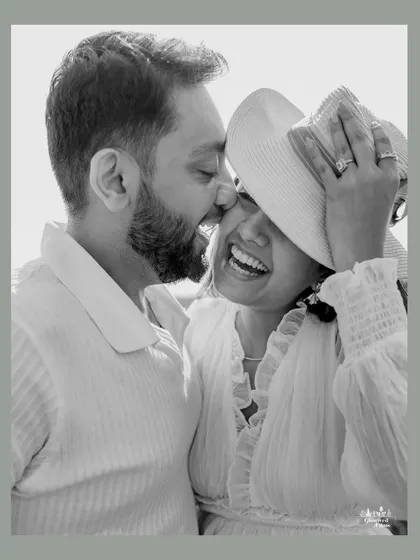 A playful and intimate black and white portrait. The hat adds a touch of fun and spontaneity, capturing a genuine moment of laughter and affection during their outdoor pre-wedding session.