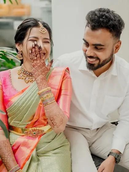 A candid, joyful moment between a couple. The bride's simple yet elegant embroidered pink blouse pairs perfectly with her multi-toned pastel saree.
