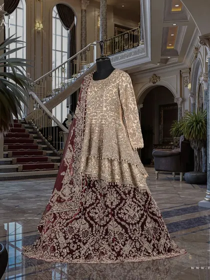 A studio shot of the gold double-layered peplum top and reddish maroon tail lehenga, showcasing exceptional craftsmanship.