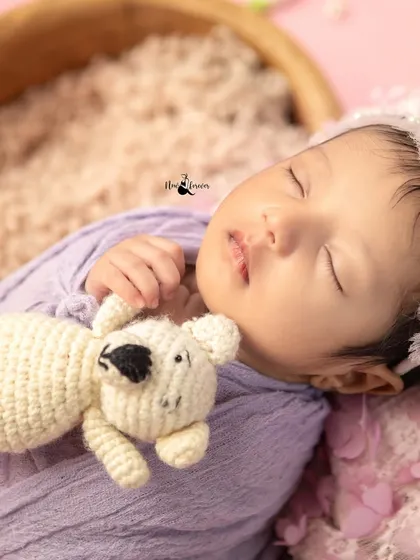 A close-up of a newborn cuddling a small teddy bear. The soft textures and gentle expression make this an incredibly sweet and tender portrait.