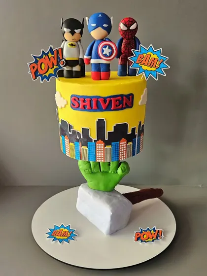 Assembling the Avengers! This superhero structure cake features a city skyline tier held up by Hulk's mighty fist, with Thor's hammer at the base. It's an action-packed cake for a true Marvel fan.