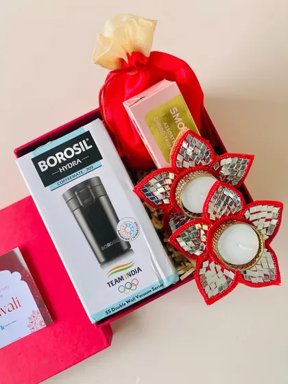 We can include branded items in our hampers, like this Borosil coffee mug, paired with festive mirror-work diyas in a red gift box.
