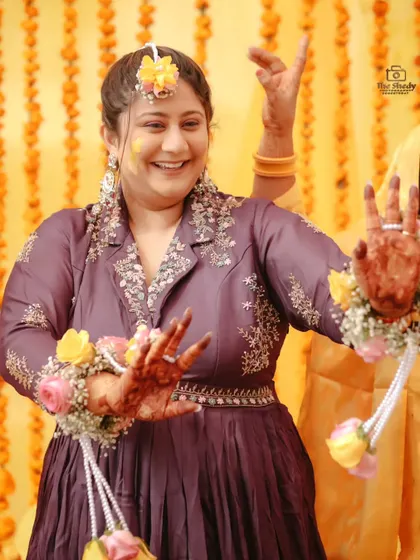 The bride showing off her henna-stained hands and dancing during her Haldi ceremony. A perfect shot capturing movement and happiness.