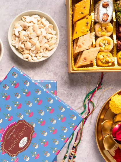 A vibrant flat lay showcasing a festive sweet box alongside traditional Rakhi elements. We use color and composition to create a visually appealing and celebratory image.