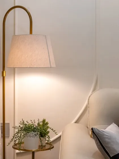 Details matter. This elegant floor lamp adds a layer of warm, ambient lighting to the living room, creating a cozy corner for reading or relaxing.