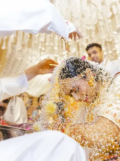 The couple is showered with rice (talambralu), a fun and significant ritual symbolizing blessings, prosperity, and happiness. The bride's expression is a mix of laughter and being overwhelmed with joy.
