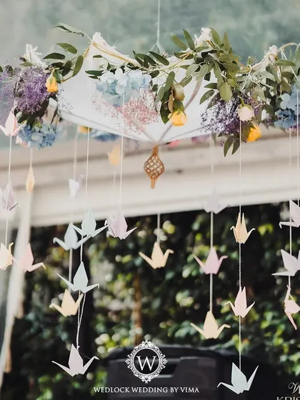 Details from a pastel-themed Mehendi, featuring an umbrella adorned with flowers and hanging origami birds. These delicate touches added a layer of playful elegance to the decor.