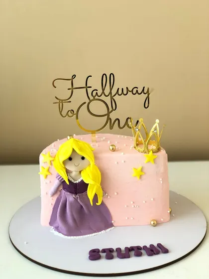 A sweet "Halfway to One" cake featuring a Rapunzel-inspired princess topper and a golden crown.