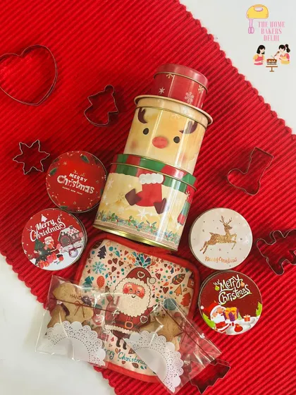 An overhead view of our complete DIY Christmas Cookie Decorating Tin. You can see the reusable festive tins, cookie cutters, and packets of plain cookies ready for your creative touch.