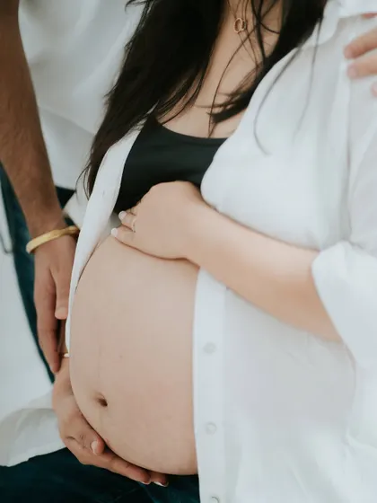 A close-up shot focusing on the baby bump, with both parents' hands. This is a powerful image that symbolizes protection, love, and unity.