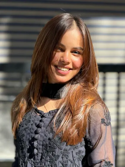 A happy client enjoying her new hair color. The warm highlights frame her face and give her a beautiful, healthy glow.