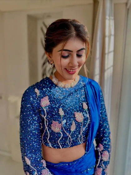 A soft smile that shows her happiness. The makeup is subtle yet impactful, perfect for her sequined blue outfit.