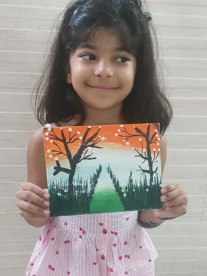 A young girl proudly holds her tricolor-themed painting. This patriotic art project was a creative way to celebrate a national holiday and express love for the country.