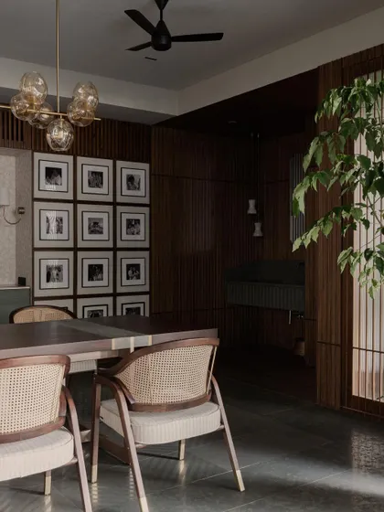 A full view of the dining room at Pràna, with its warm wood paneling and statement chandelier. The gallery wall adds a personal touch, making the space feel truly lived-in.