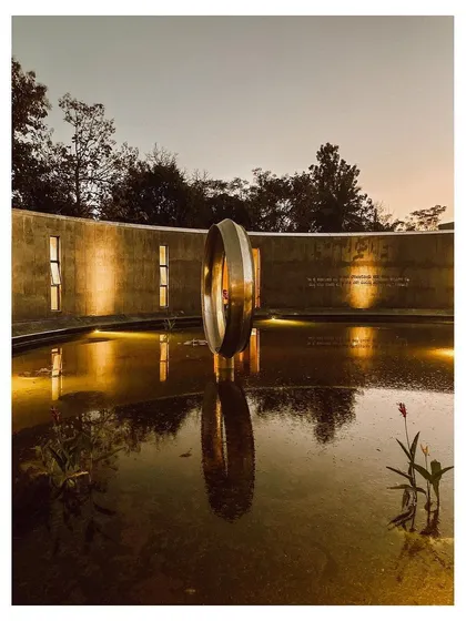 A quiet evening at the memorial's water court. The artificial lighting creates a dramatic reflection of the central sculpture, turning the space into a focal point of calm and beauty.