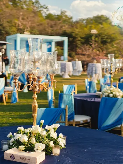 A close up of the tablescape at a blue themed Mehendi Sangeet. A classic candelabra paired with simple white florals creates a look of timeless elegance.